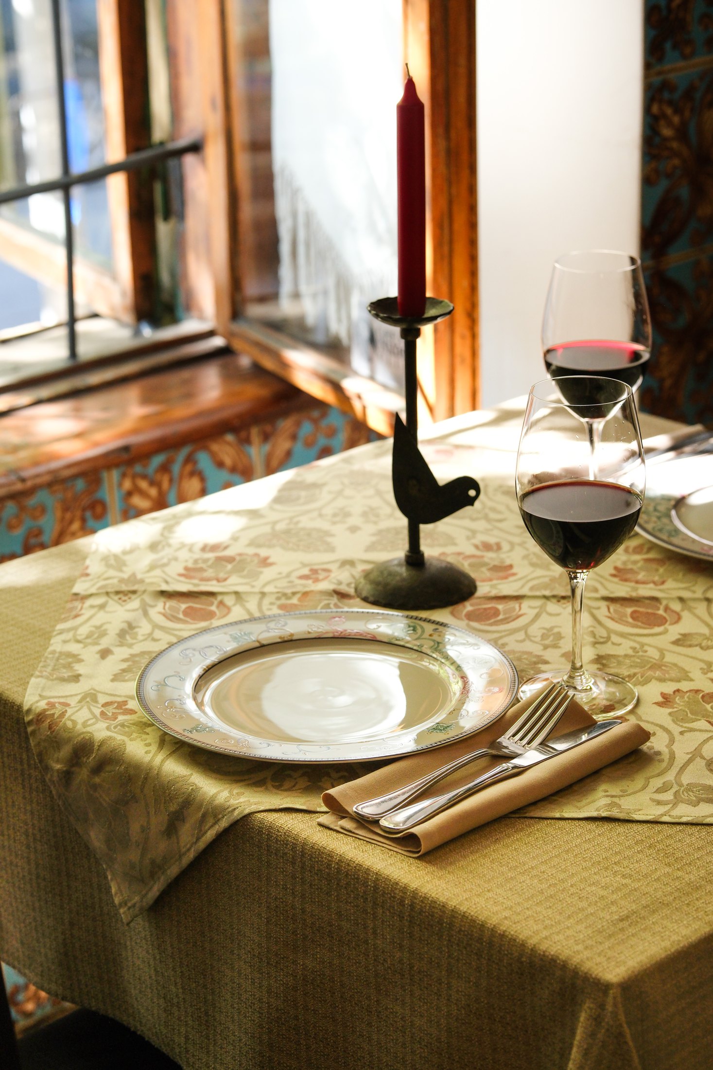 Sunlit Dolmama table with red wine glasses and candle